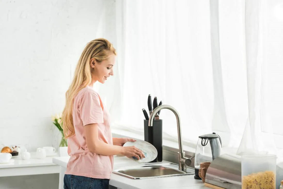 Person washing dishes at a kitchen sink